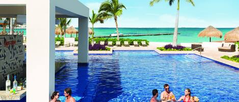 A swimming pool area with lounge chairs and palm trees, overlooking a beach.