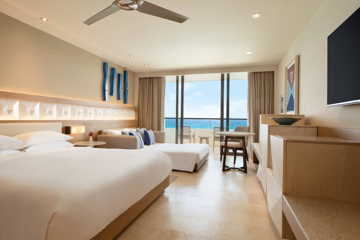 Una habitació d'hotel amb un llit gran, una taula de treball i vistes a l'oceà.