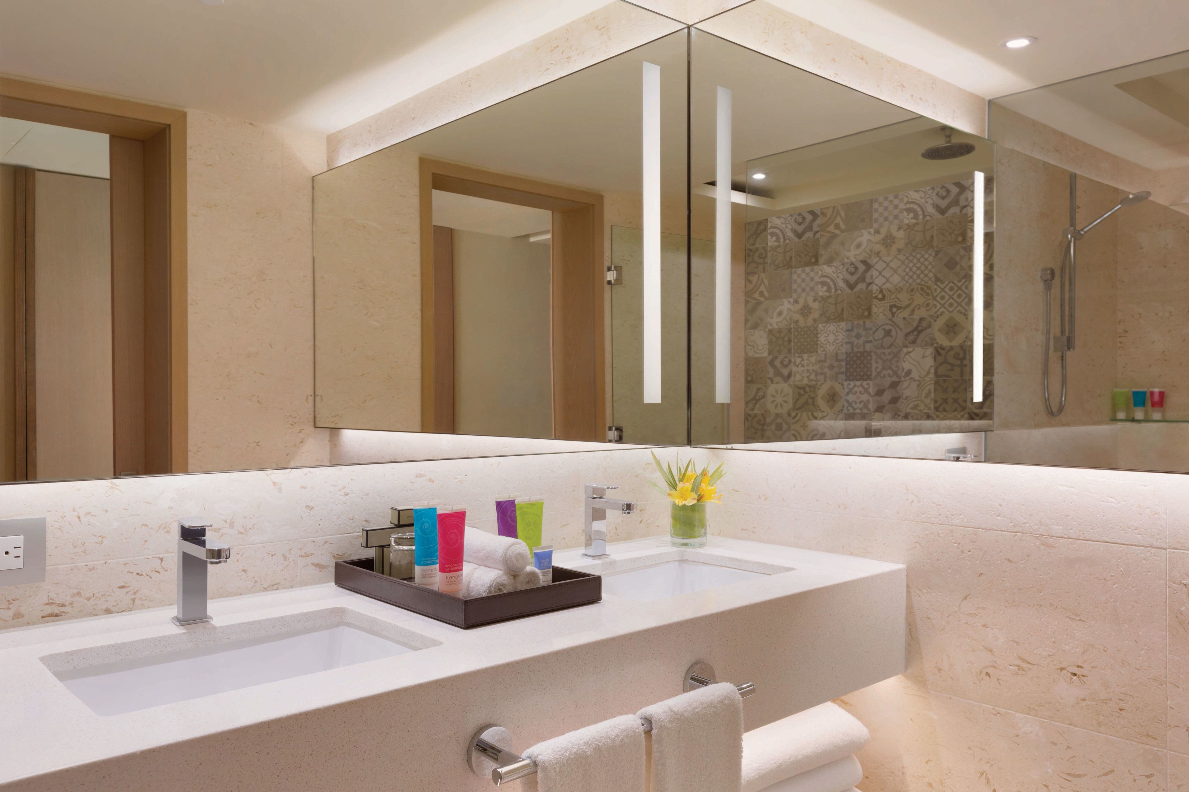 A modern bathroom with two sinks, a large mirror, and a shower area.