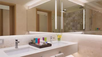 A modern bathroom with two sinks, a large mirror, and a shower area.