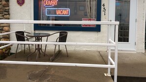 A hotel with a neon sign indicating it's open and not vacant. There are two chairs and a table outside. - Motel Sainte-Flavie (Sainte-Flavie)