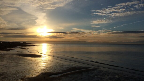 A beach with the sun setting over the horizon, creating a calm and serene atmosphere. - Motel Sainte-Flavie (Sainte-Flavie)