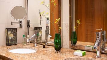 Un baño con dos lavamanos, un espejo y un florero verde con flores amarillas.
