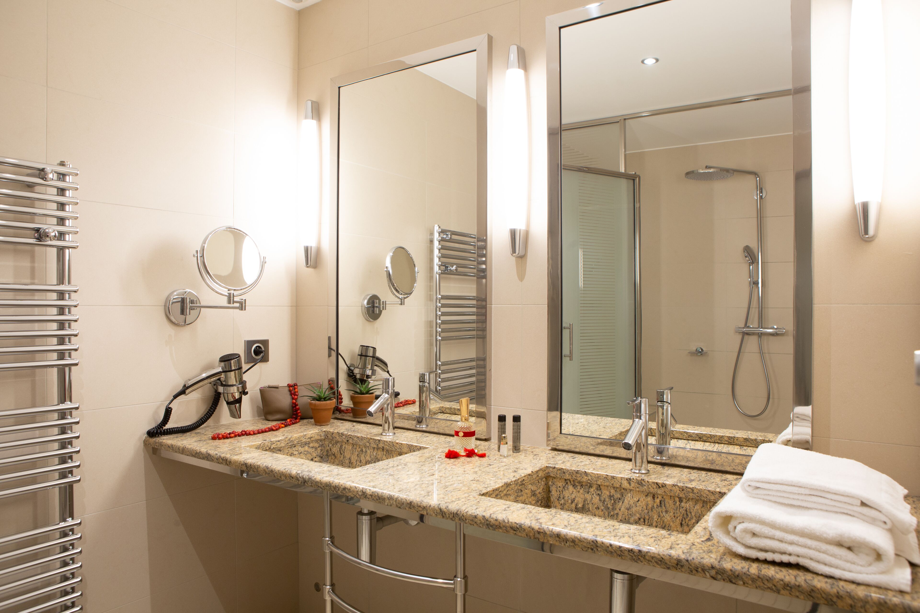 Een badkamer met twee wastafels, een grote spiegel, een handdoekhouder en een douche.