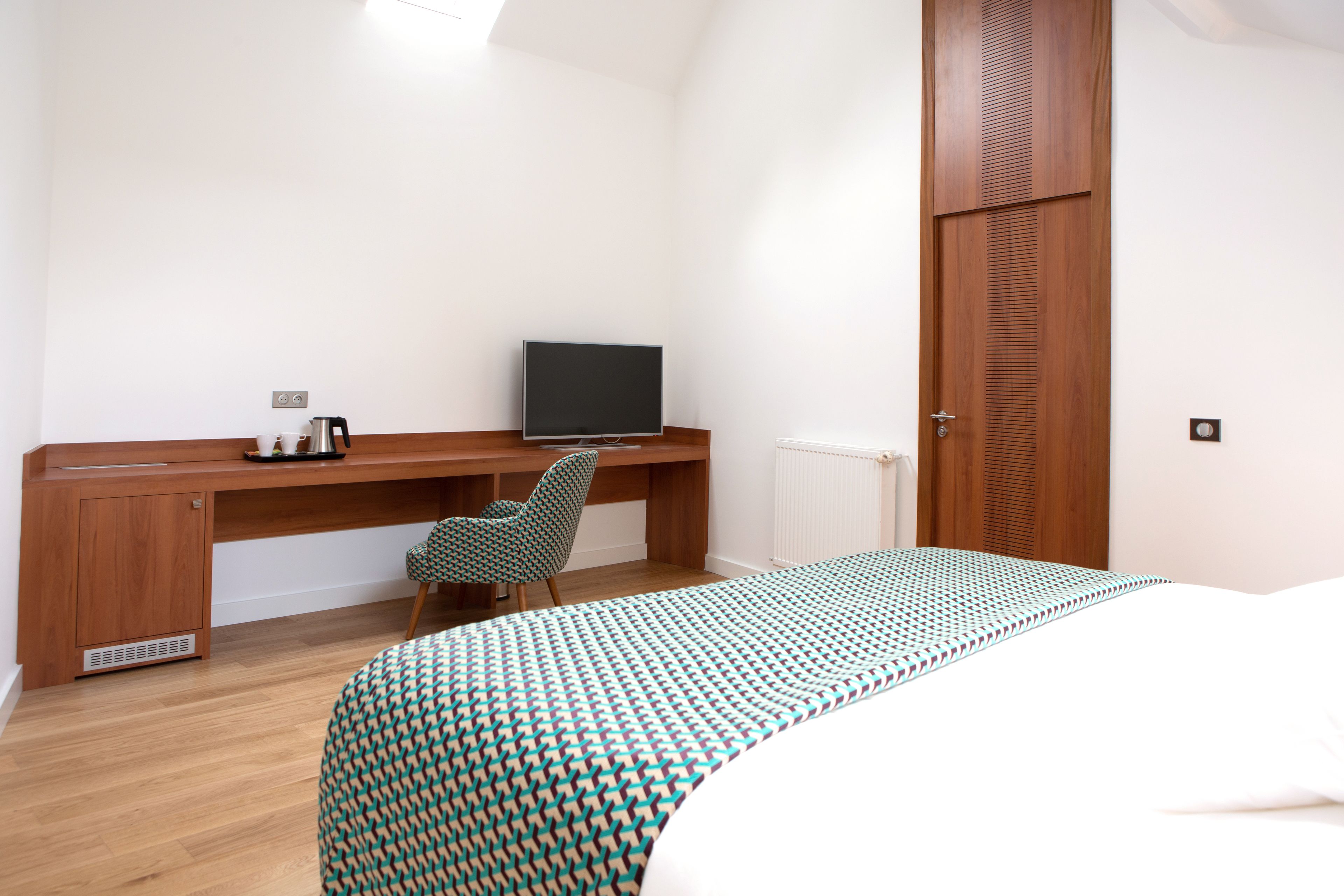 Une chambre à coucher comprenant un lit, un bureau, une chaise, une télévision et une armoire.