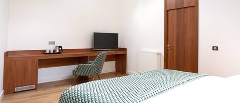 Une chambre à coucher comprenant un lit, un bureau, une chaise, une télévision et une armoire.