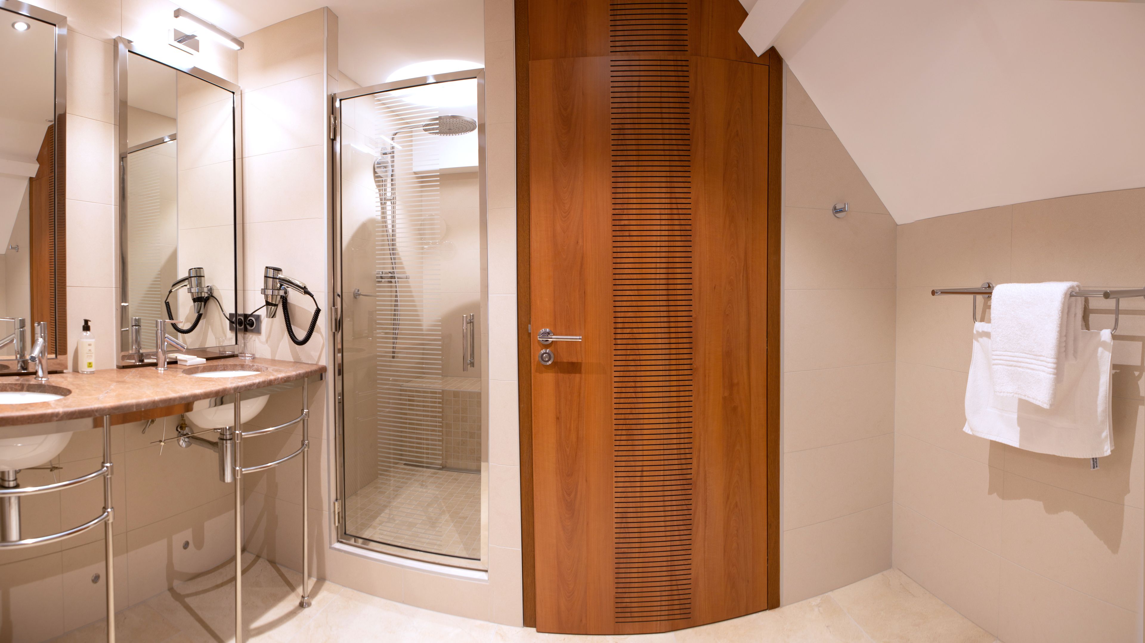 A modern bathroom with a wooden door, a glass shower enclosure, and a vanity with a mirror and sink.