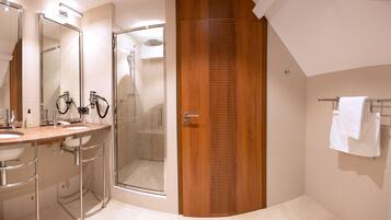 A modern bathroom with a wooden door, a glass shower enclosure, and a vanity with a mirror and sink.