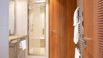 Une salle de bain moderne avec une douche à parois de verre, un meuble-lavabo en bois et un porte-serviettes.
