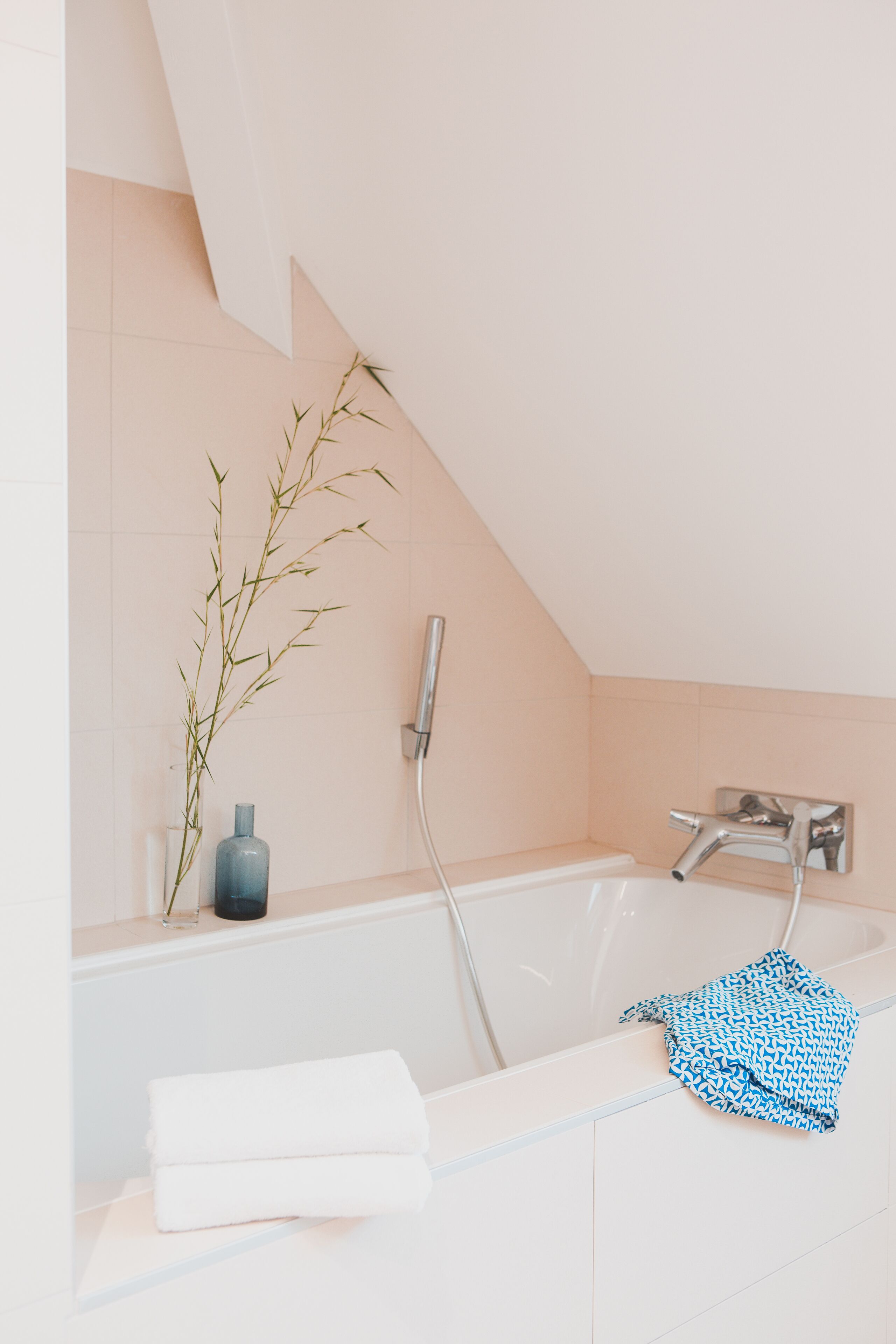 Une salle de bain moderne avec une baignoire, un porte-serviettes et une plante en bambou.
