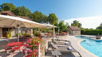 A poolside area with lounge chairs, a table, and umbrellas.