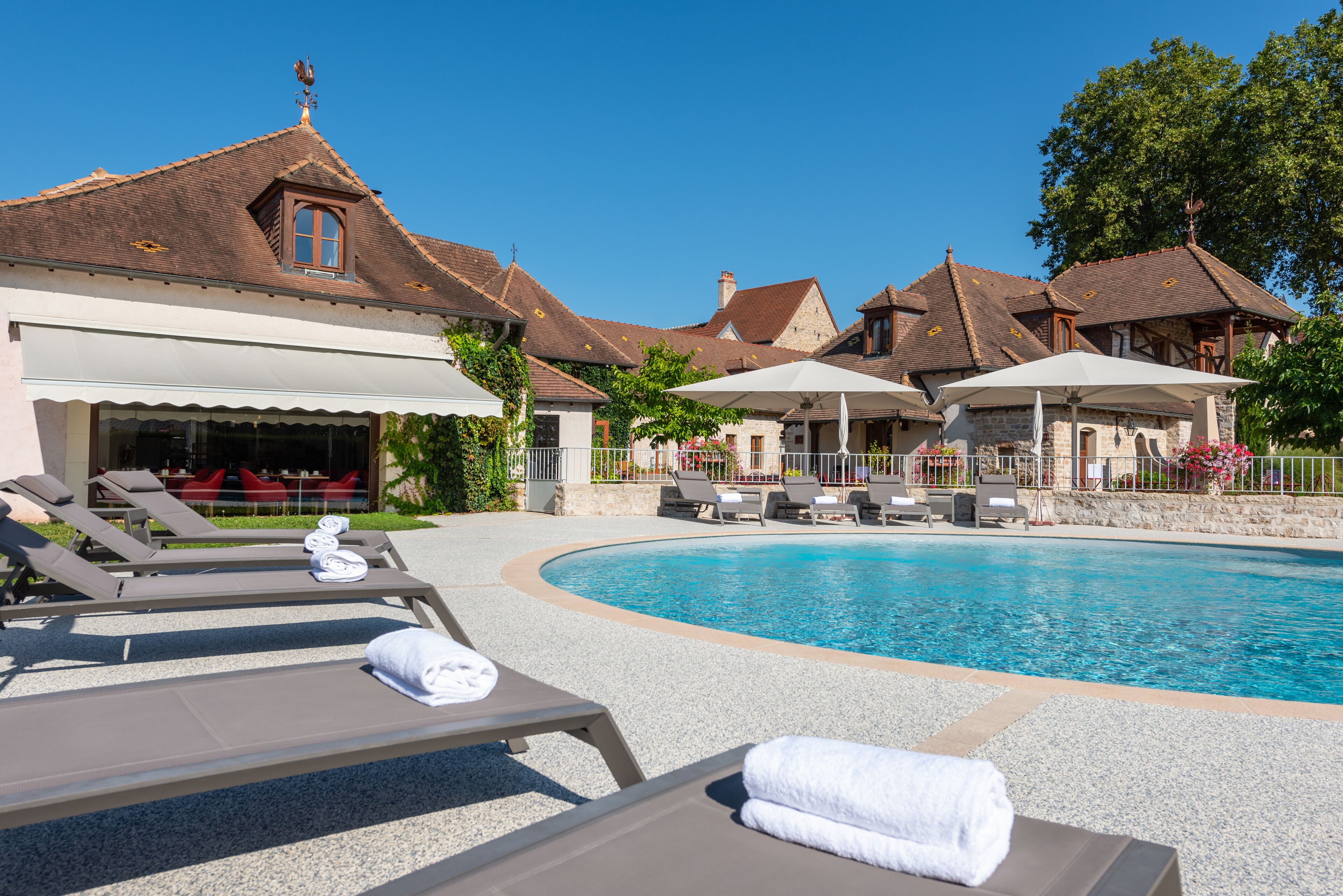 A resort with a swimming pool, lounge chairs, and a covered outdoor seating area.