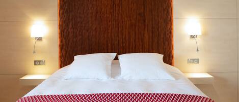 A hotel room with a large bed, two bedside lamps, and a wooden headboard.