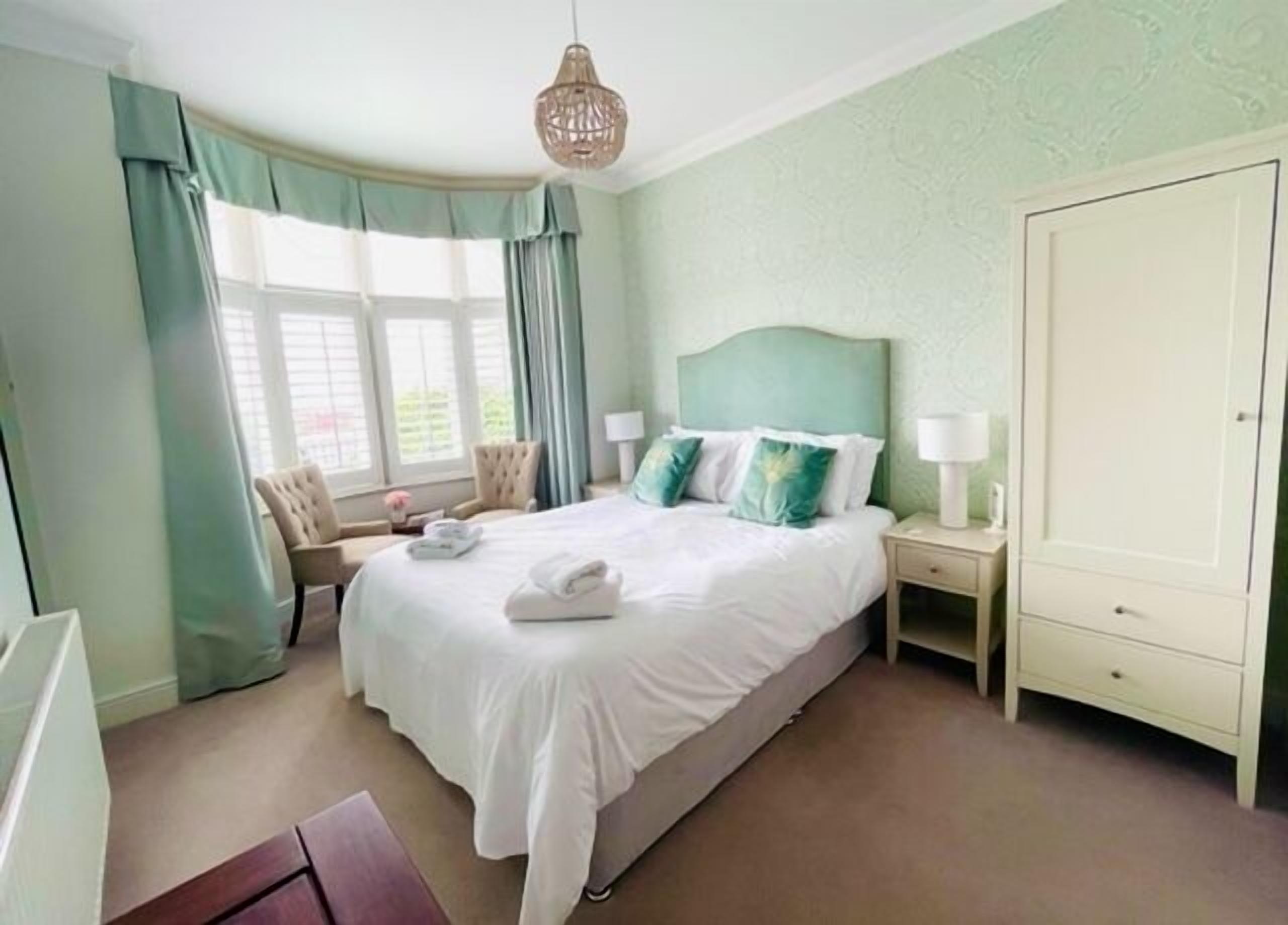 Een hotelkamer met een groot bed, een nachtkastje, een garderobe en een raam met gordijnen.