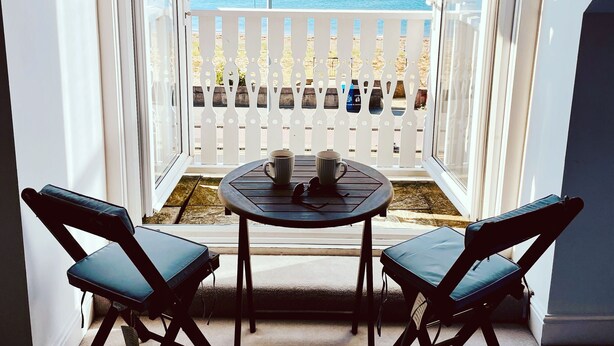 En balkon med havudsigt, et bord med to stole og et gelænder.