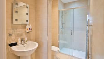 A modern bathroom with a glass-enclosed shower, a white sink, and a mirror with lights.