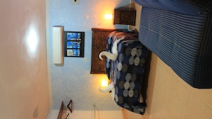 Ein Schlafzimmer mit Bett, Nachttisch, Wand-Fernseher und Deckenleuchte.