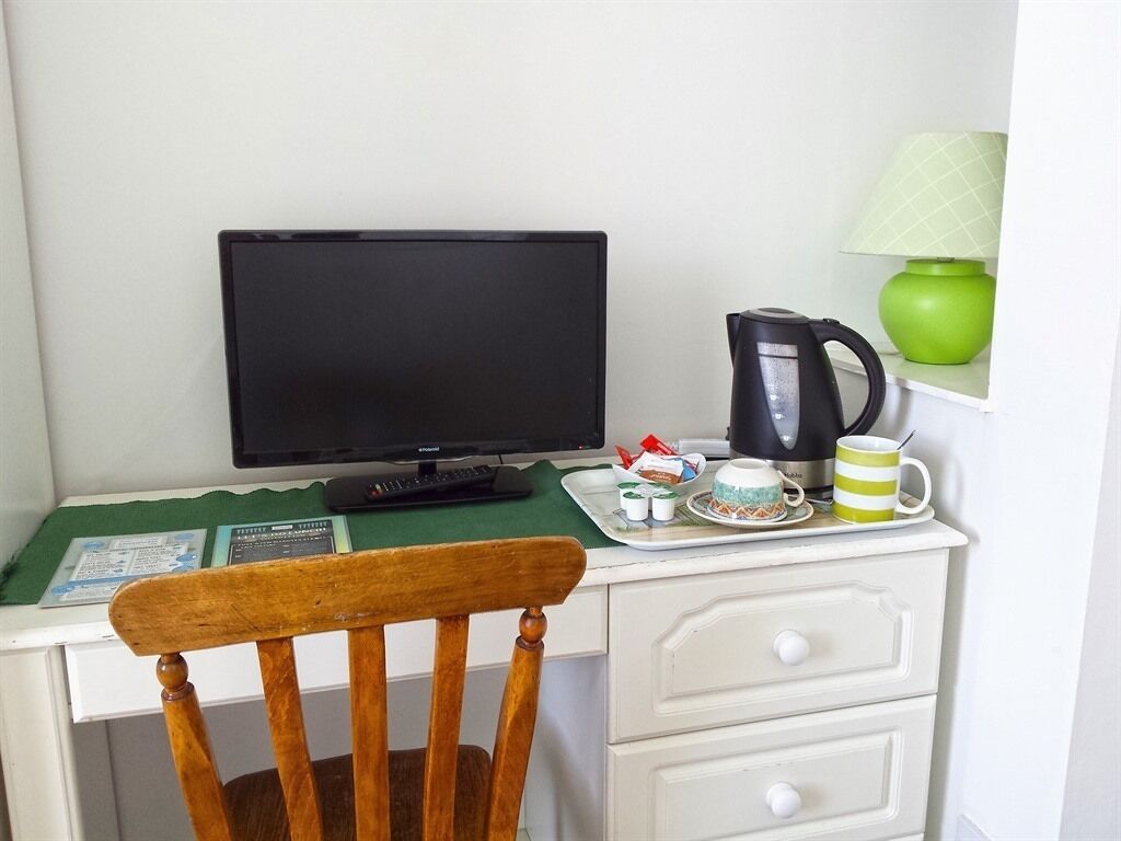 A small workspace with a computer, a coffee maker, and a tray with cups and a mug.