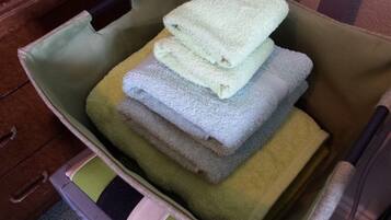 A storage bin with a handle, containing folded towels in various colors.