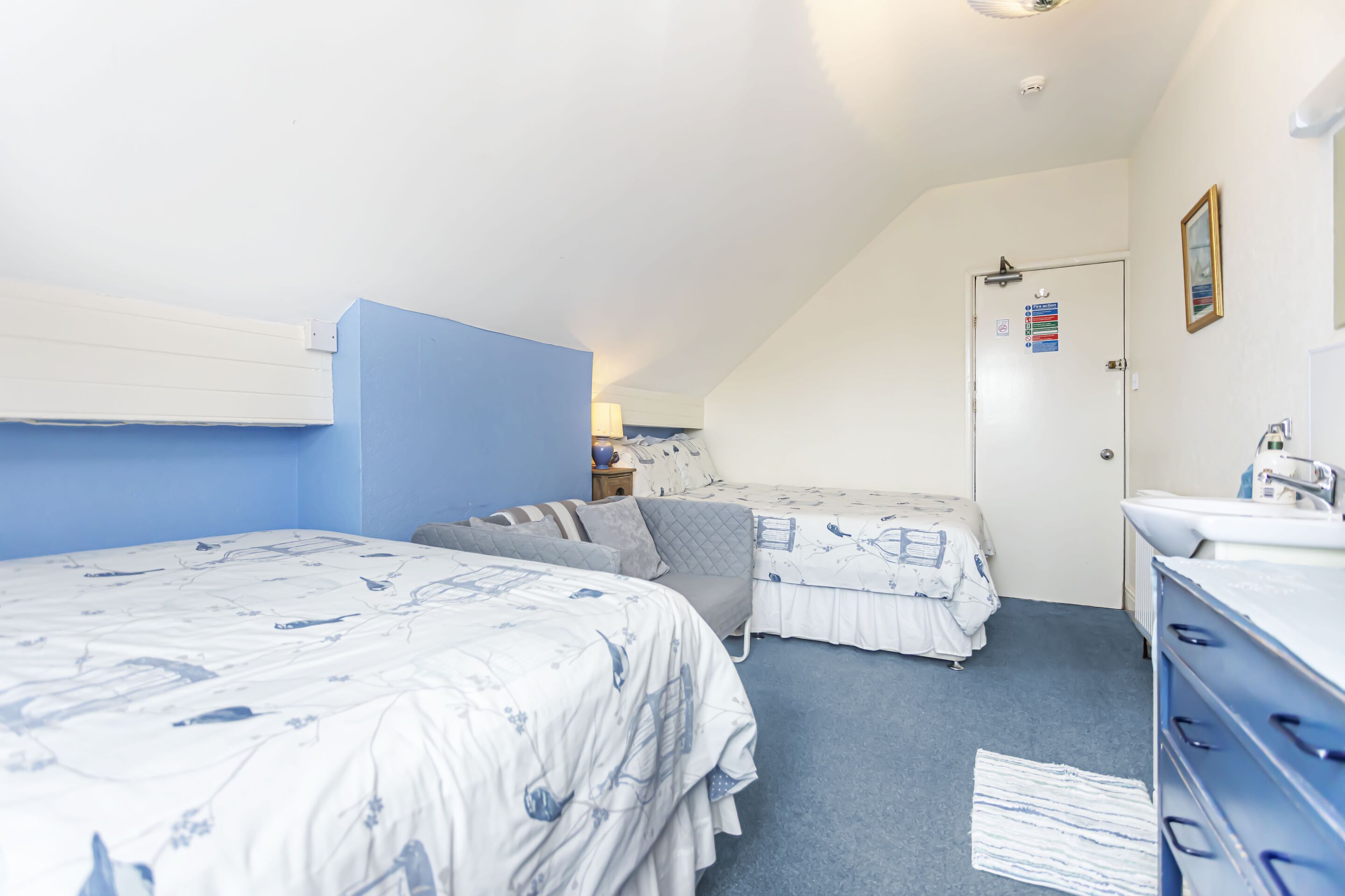 Un dormitorio con dos camas, un aparador y una puerta con un letrero.