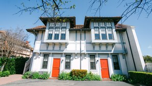 Un bâtiment à deux étages doté d’une façade symétrique, avec une entrée centrale flanquée de deux portes rouges et un toit recouvert de tuiles.