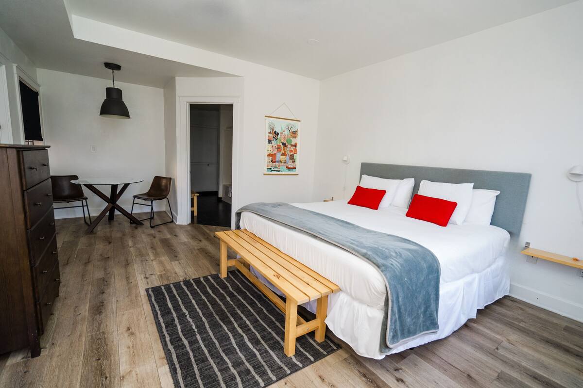 A bedroom with a bed, a wooden bench, a desk, and a chair.