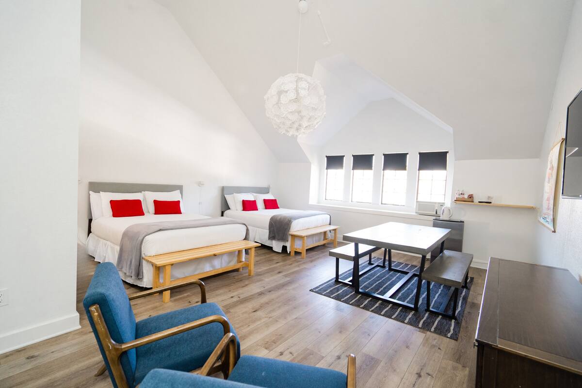 A modern, well-lit room with a loft bed, a desk, and a chair.