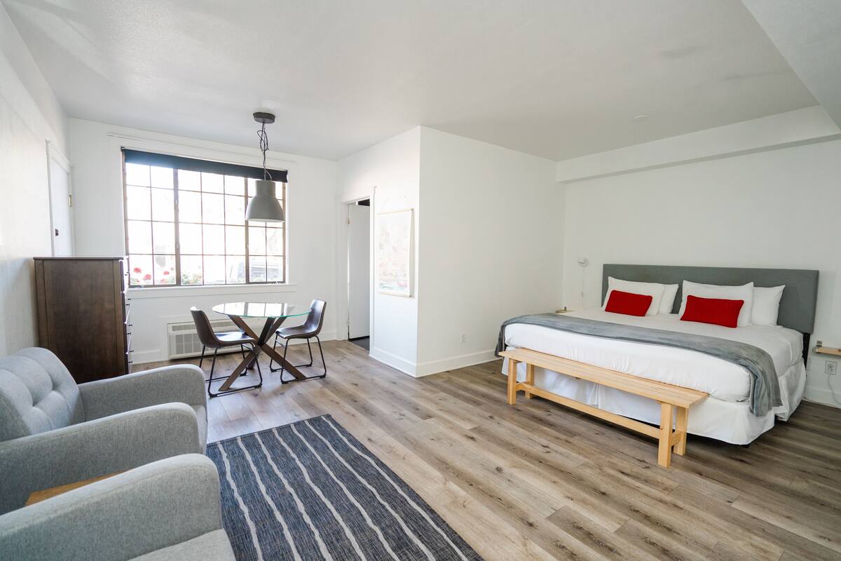 A modern bedroom with a large bed, a dining table, and two armchairs.
