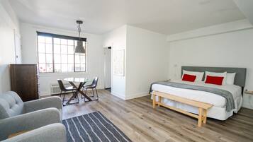 Un dormitorio moderno con una cama grande, una mesa de comedor y dos sillones.