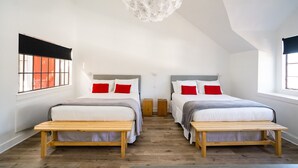 Une chambre avec deux lits, des bancs en bois et un lustre unique.
