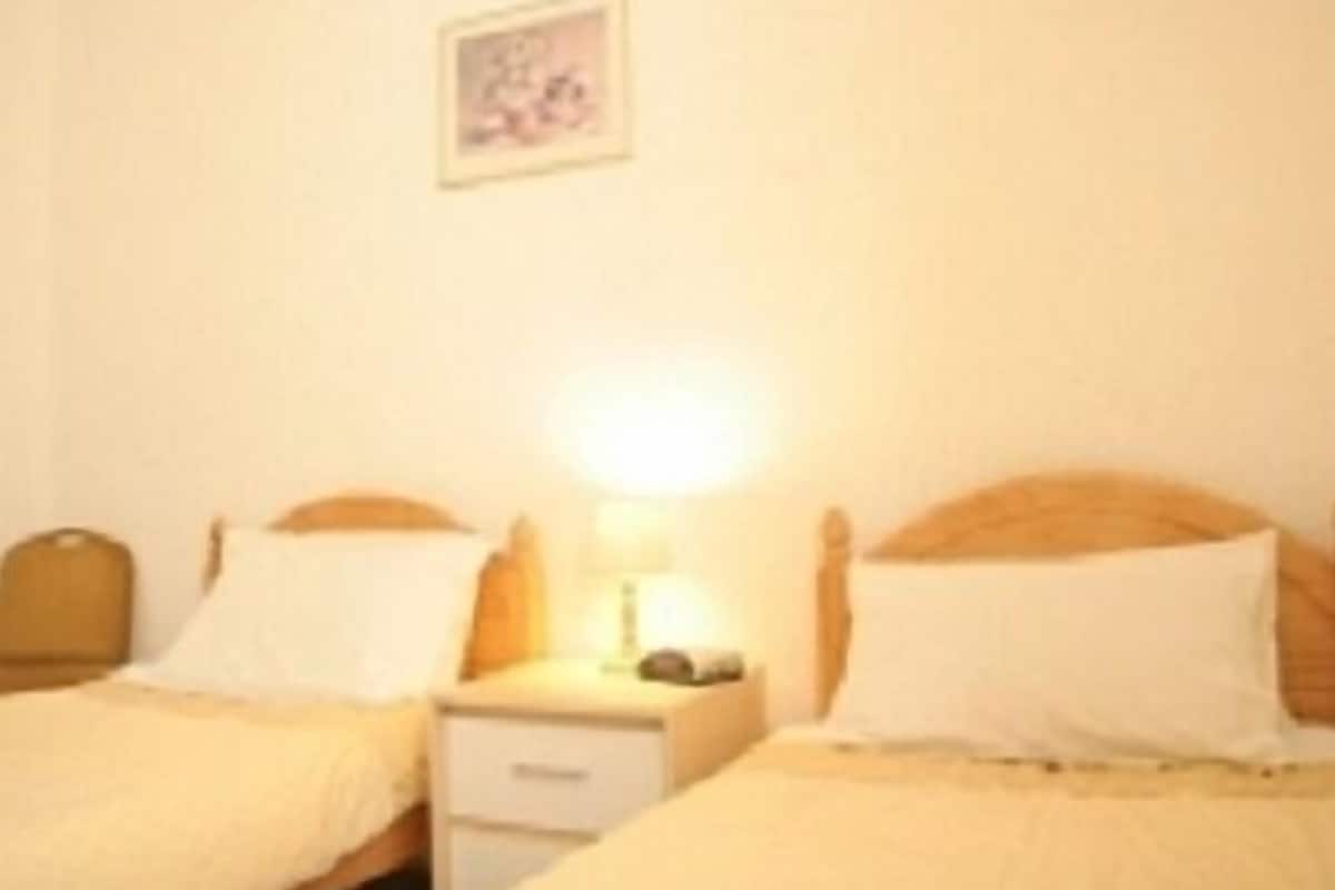 A bedroom with two single beds, a nightstand, and a wall-mounted picture.