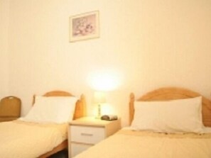 A bedroom with two single beds, a nightstand, and a wall-mounted picture. - Morrisy House (Blackpool)