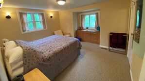A bedroom with a bed, dresser, and two windows. - Teddy Bear Bed & Breakfast (Bancroft)