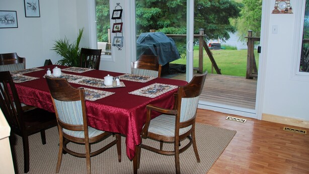 A dining room with a table set for four, wooden chairs, and a red tablecloth. - Teddy Bear Bed & Breakfast (Bancroft)