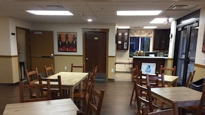 A dining area with wooden tables and chairs, a kitchen area with a counter, and a door marked with the number 101.