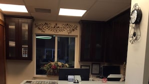 A reception desk with a digital display, a clock, and a window with a view of the outside.