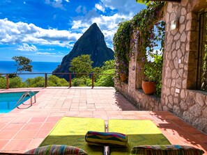 Una zona junto a la piscina con vistas a la montaña y al océano.