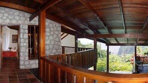 A curved staircase with stone walls and a wooden railing, leading to a room with a bed and a window.