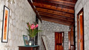 A hallway with stone walls, wooden beams, and a tiled floor.