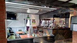 Zona de bar con taburetes, una barra con botellas y un cartel de salida.