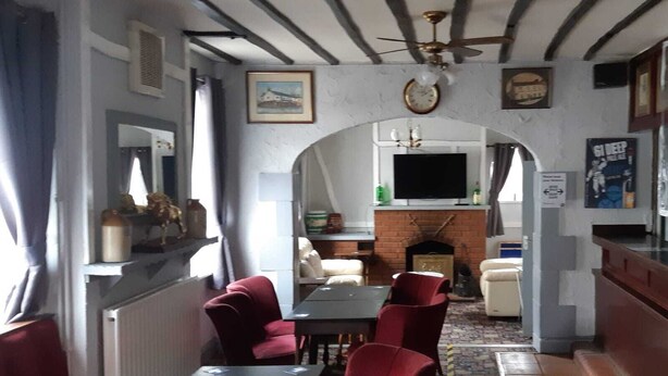 Un comedor con chimenea, sillas rojas, una mesa y un reloj en la pared.