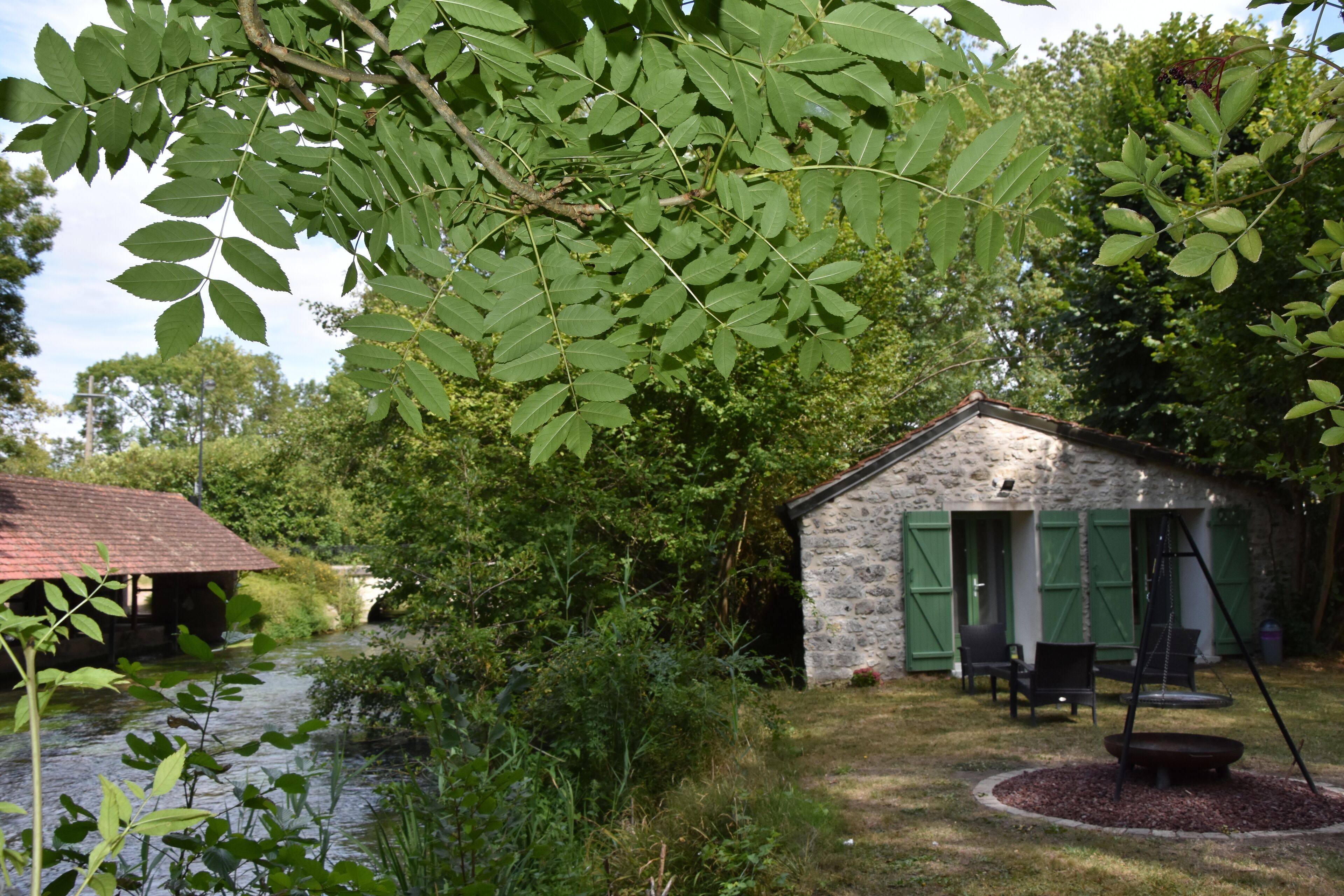 Ein rustikales Steinhaus mit einer kleinen Veranda und einer Sitzgelegenheit im Freien.