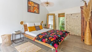 Un dormitorio con una cama, una mesita de noche, un espejo y un ventanal grande.