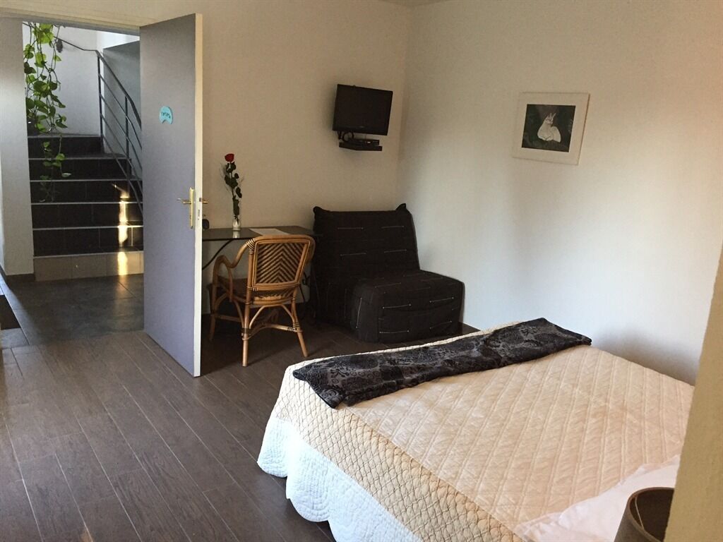 A bedroom with a bed, a desk, a chair, a television, and a staircase leading to another room.