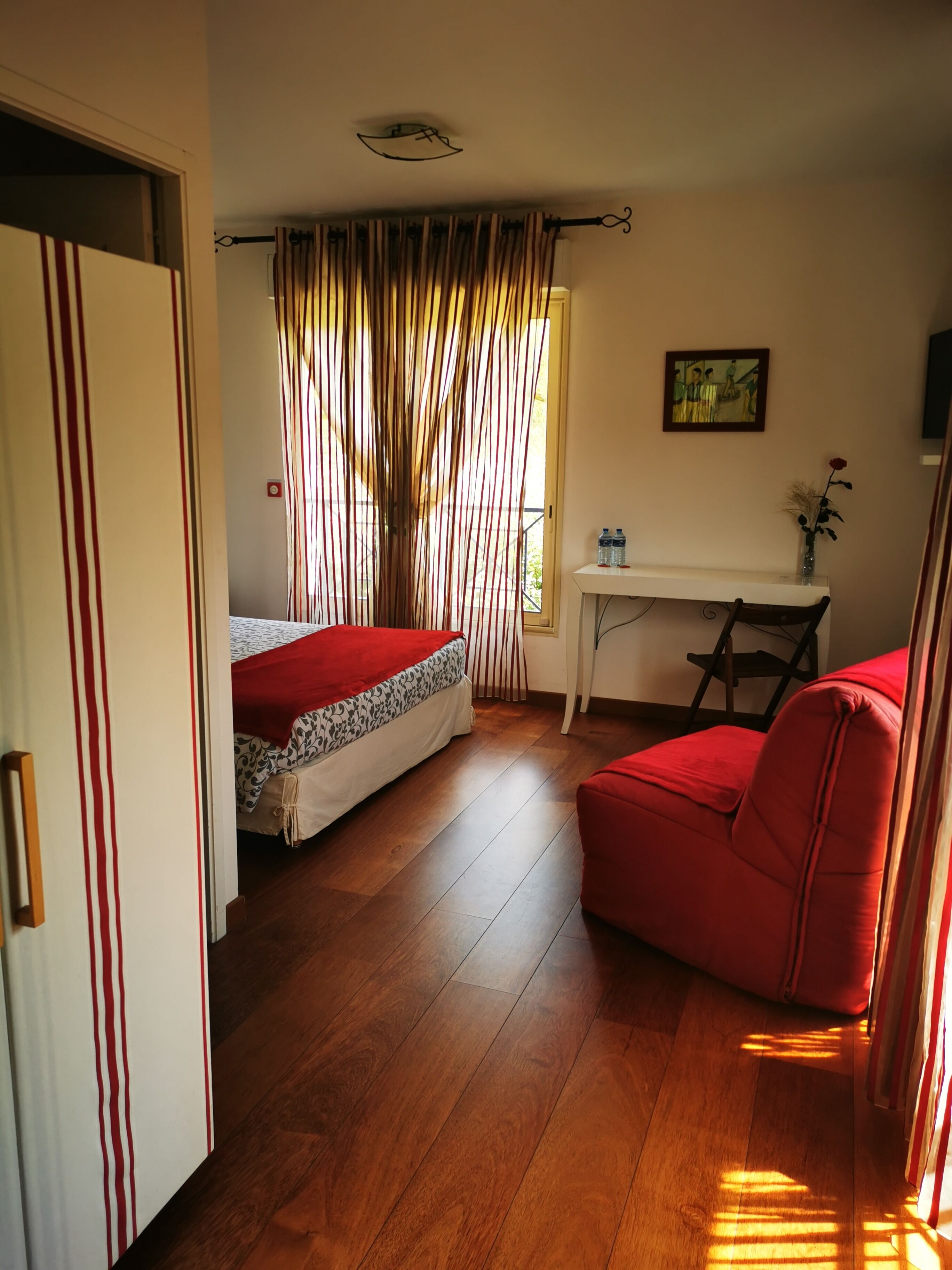 A room with a bed, a desk, and a red chair.