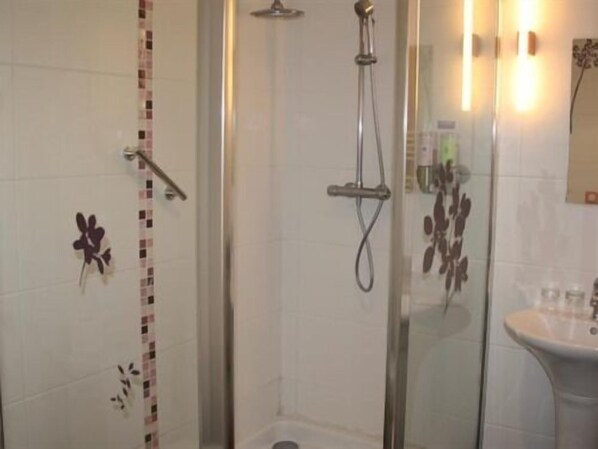 Une salle de bain avec une douche à parois de verre, un lavabo blanc et des carreaux décoratifs sur les murs.