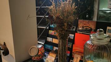 A glass display table with various items including a vase with dried plants, a jar, and some books.