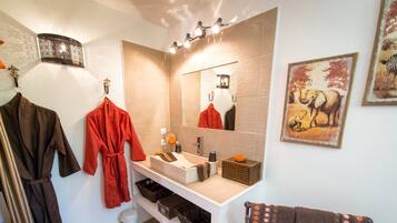 Un baño con tocador blanco, un espejo, un perchero para toallas, un lavabo y un adorno de pared.