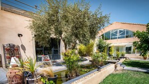 A garden with a small pond, potted plants, and a patio area. - Villa Ambrosia (Narbonne)