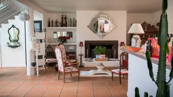 A spacious living room with a fireplace, a staircase, and a variety of decorative items on shelves.